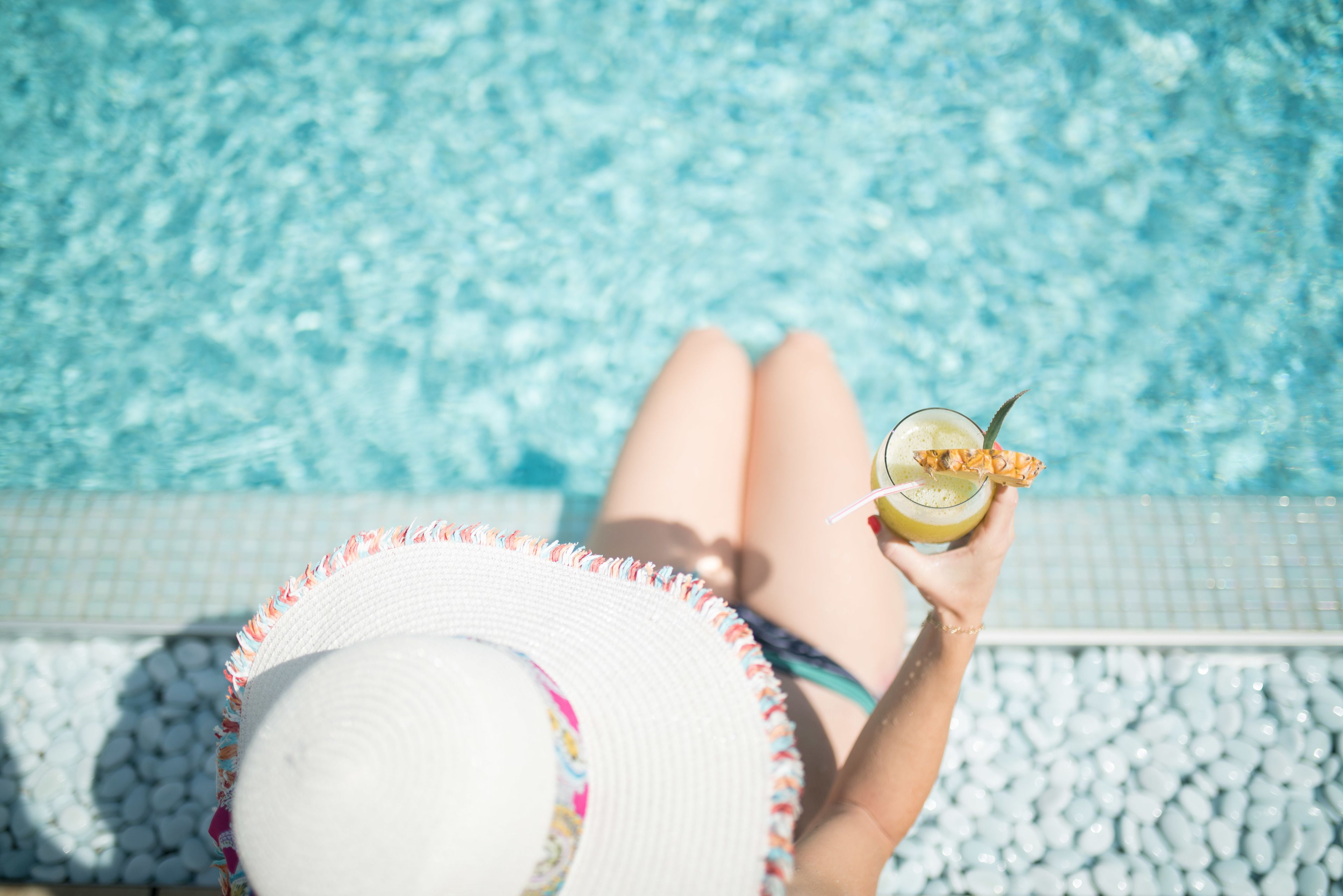 A person relaxing by a pool with a drink in hand.