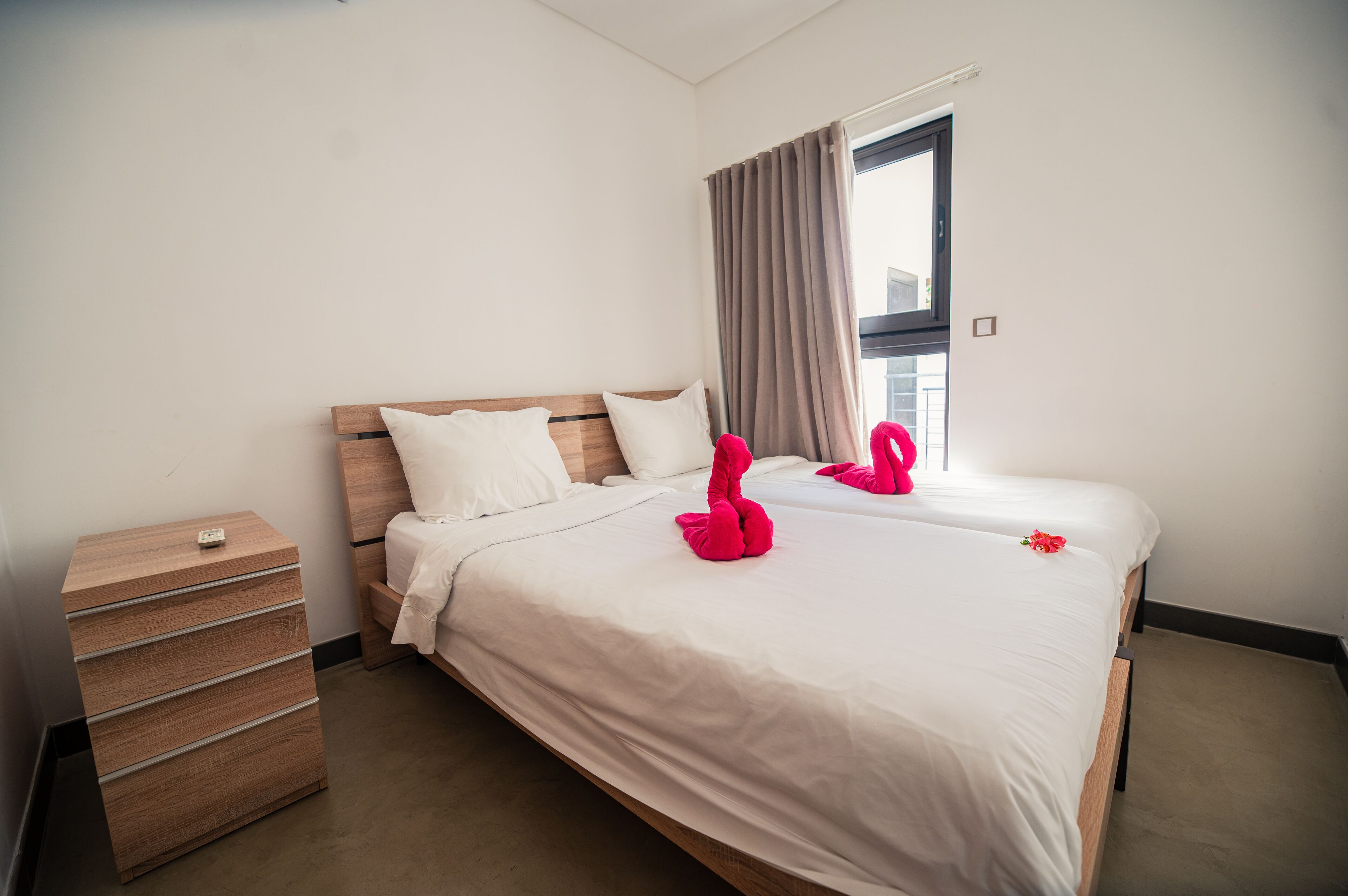 A hotel room with two beds, a wooden nightstand, and a dresser.