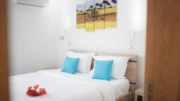 Una cama bien hecha con ropa de cama blanca y azul, un cabecero de madera y un aire acondicionado de pared.