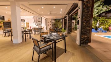 A restaurant with indoor seating and a pool area.