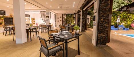 Un ristorante con posti a sedere interni e una zona piscina.