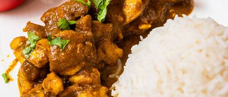 A plate of curry with rice and two side dishes.