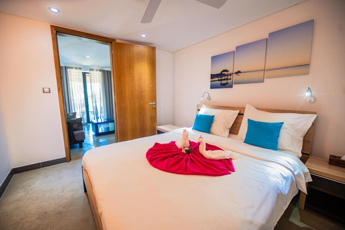 A hotel room with a large bed, a wooden door, and a view of the outside.