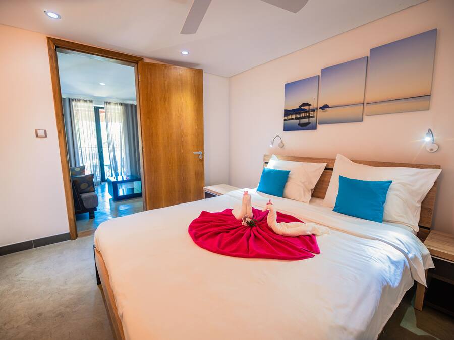 A hotel room with a large bed, a wooden door, and a view of the outside.