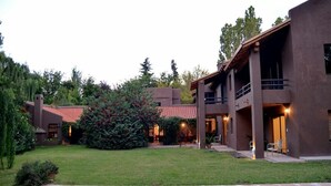 Una moderna casa a due piani con piscina, circondata da un prato curato e alberi.
