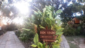 Un letrero con los textos 'Bem Vindo' y 'Recepción' en un jardín.