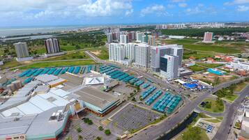A high-rise building complex with multiple floors, a parking area with blue-roofed structures, and a river in the background.