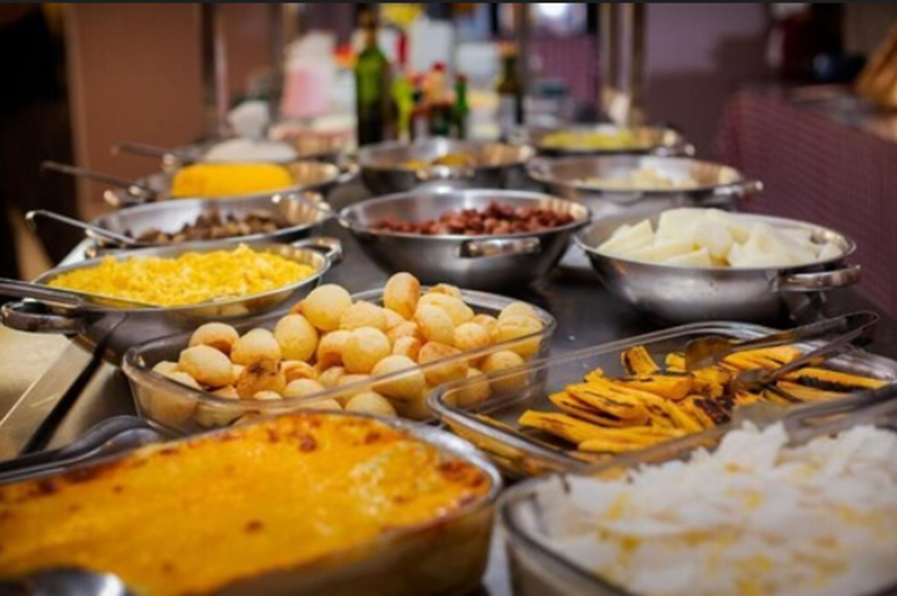 Buffet com diversos pratos, incluindo arroz, batatas e diferentes tipos de carne.