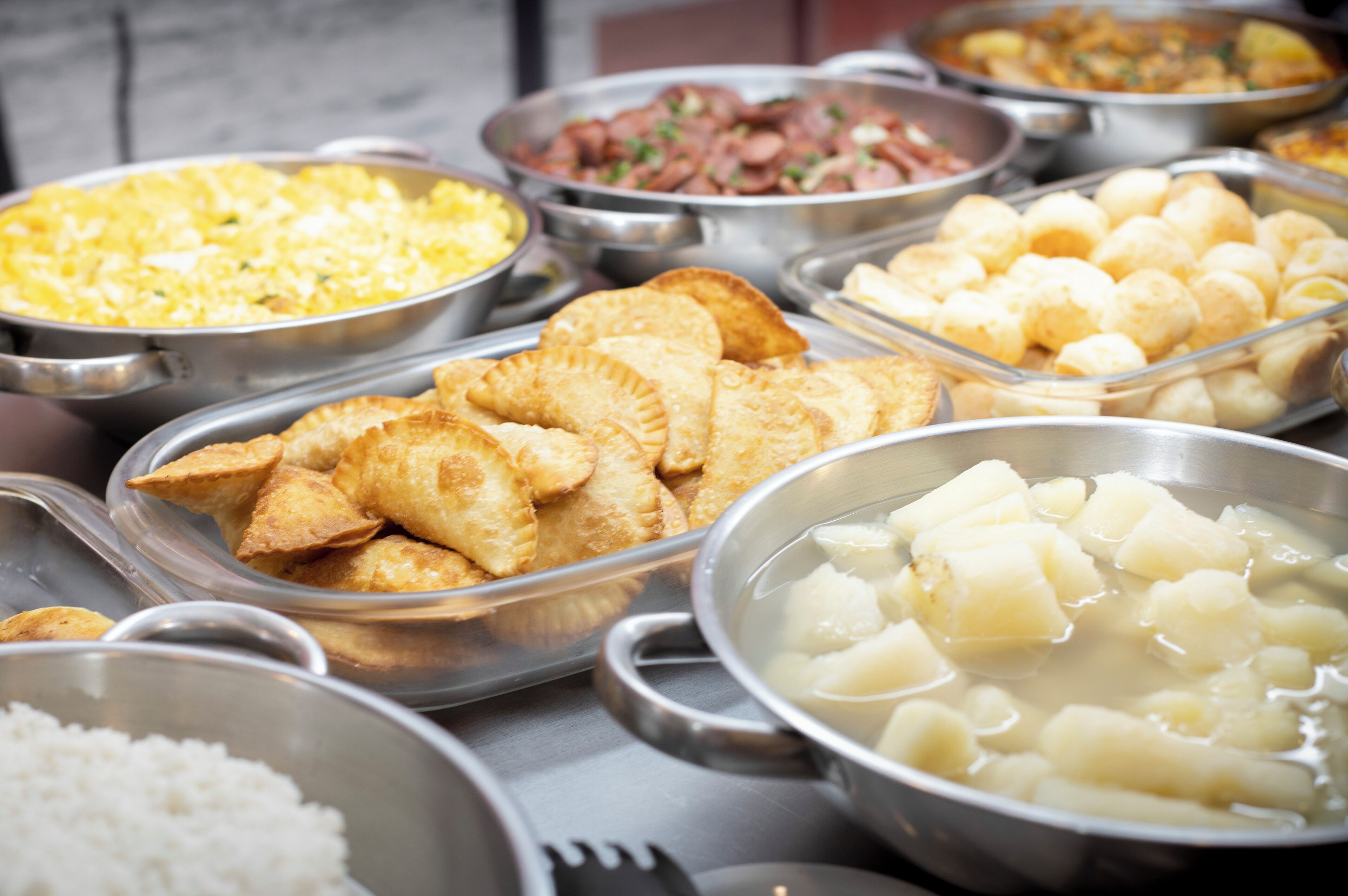 A buffet with various food items including rice, potatoes, and fried pastries.