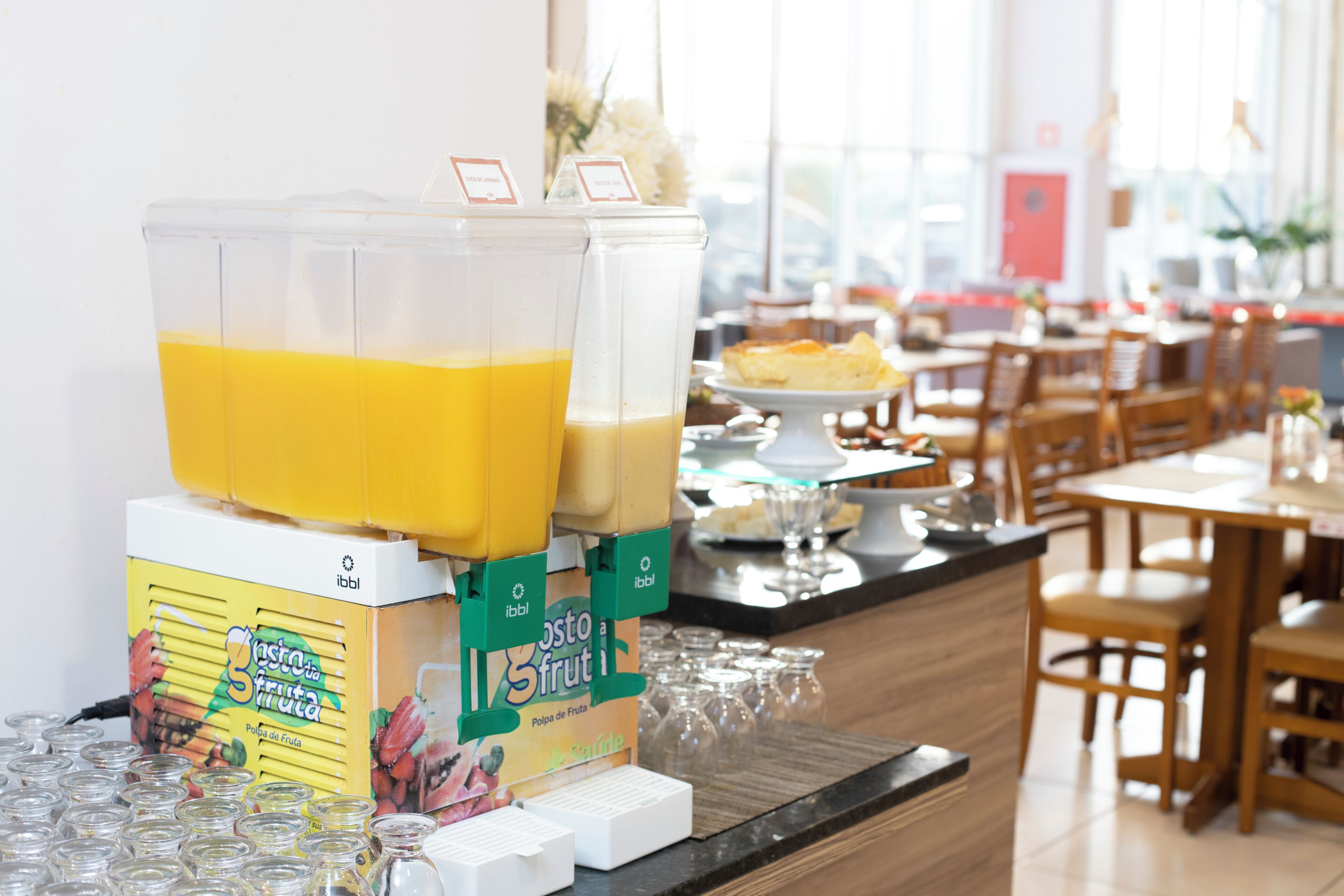 Un buffet pour le petit-déjeuner avec des distributeurs de jus, une sélection de jus de fruits en portions individuelles et divers produits pour le petit-déjeuner.