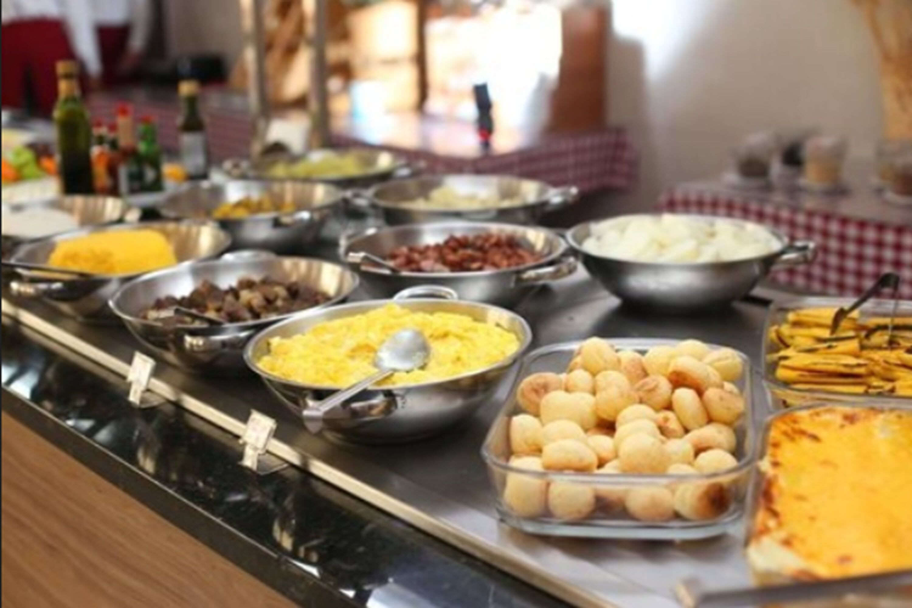 Un bufé con diversas opciones de comida, como huevos revueltos, salchichas y queso.