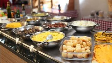Un bufé con diversas opciones de comida, como huevos revueltos, salchichas y queso.