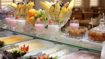 Un bufé con diversos alimentos, incluyendo frutas, lácteos y carnes.