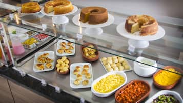A buffet with various baked goods, pastries, and side dishes.