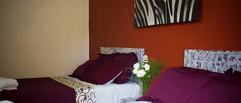 Habitación de hotel con dos camas, cada una con una colcha estampada, cabecero con diseño texturizado y una obra de arte con estampado de cebra colgada en la pared.