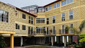 A courtyard with stone flooring, a multi-story building with balconies, and potted plants.