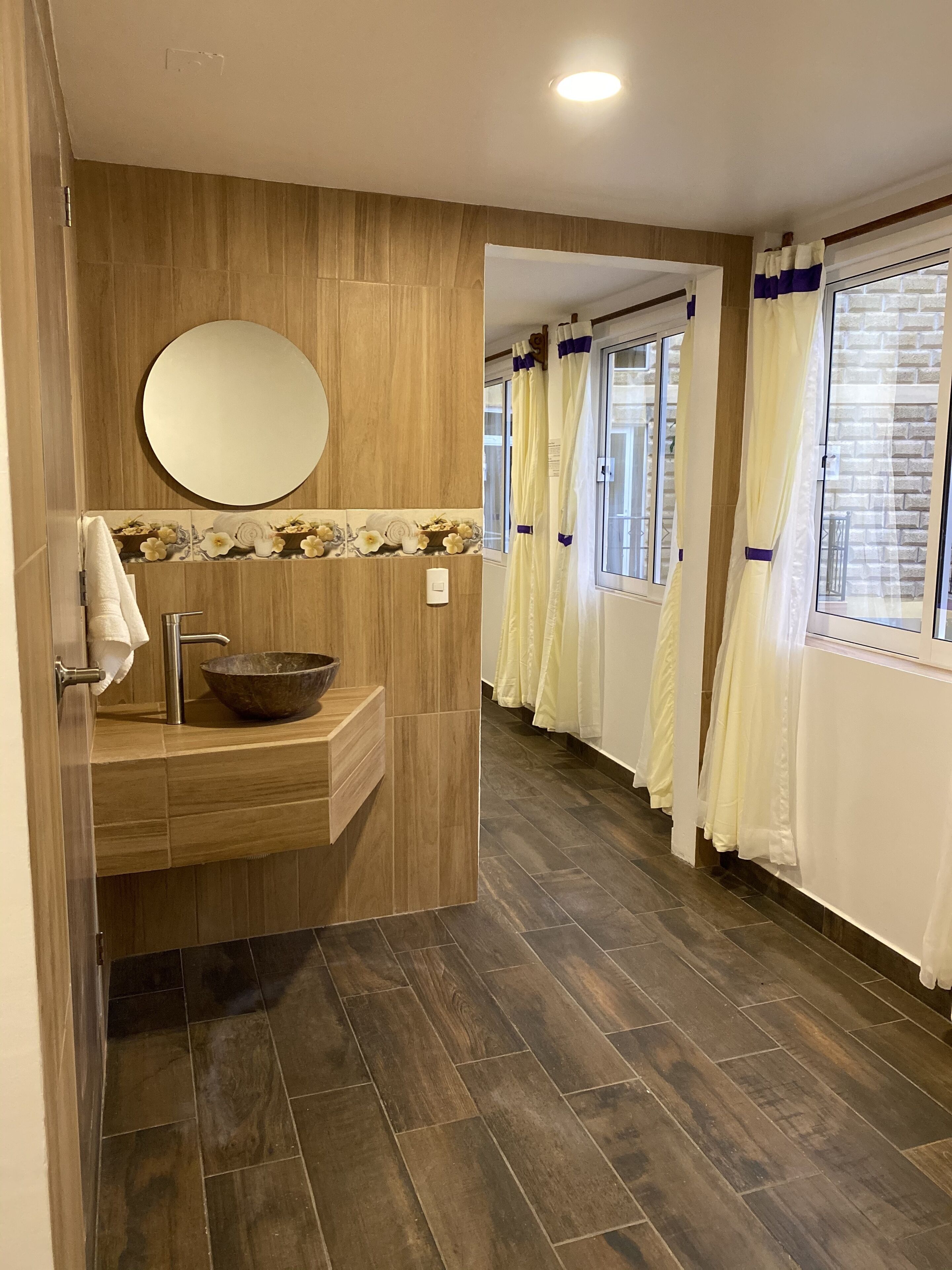 A modern bathroom with a wooden vanity, a round mirror, and a bowl sink.