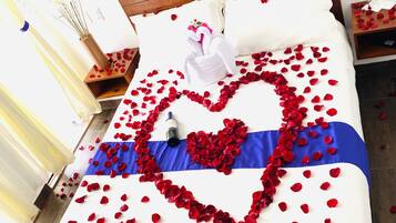 Una cama con un arreglo de pétalos de rosa en forma de corazón y una colcha a rayas azul y blanca.