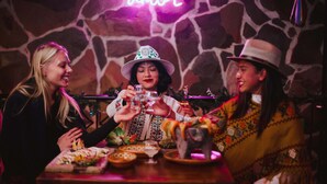A group of people toasting with drinks at a table with various dishes and glasses.