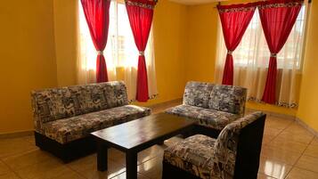 A room with two patterned sofas, a wooden coffee table, and red curtains.