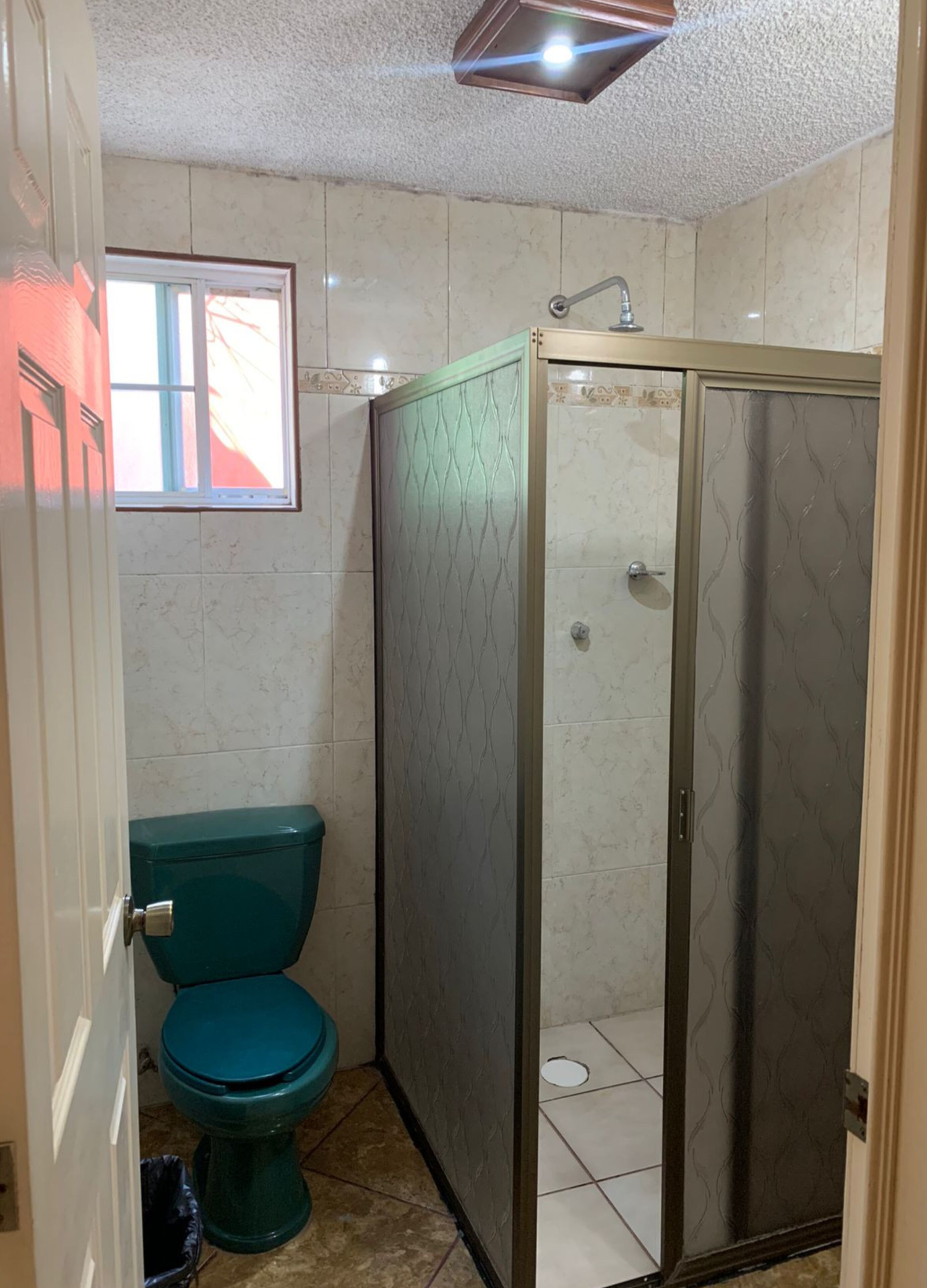 Un baño con inodoro, ducha y ventana.