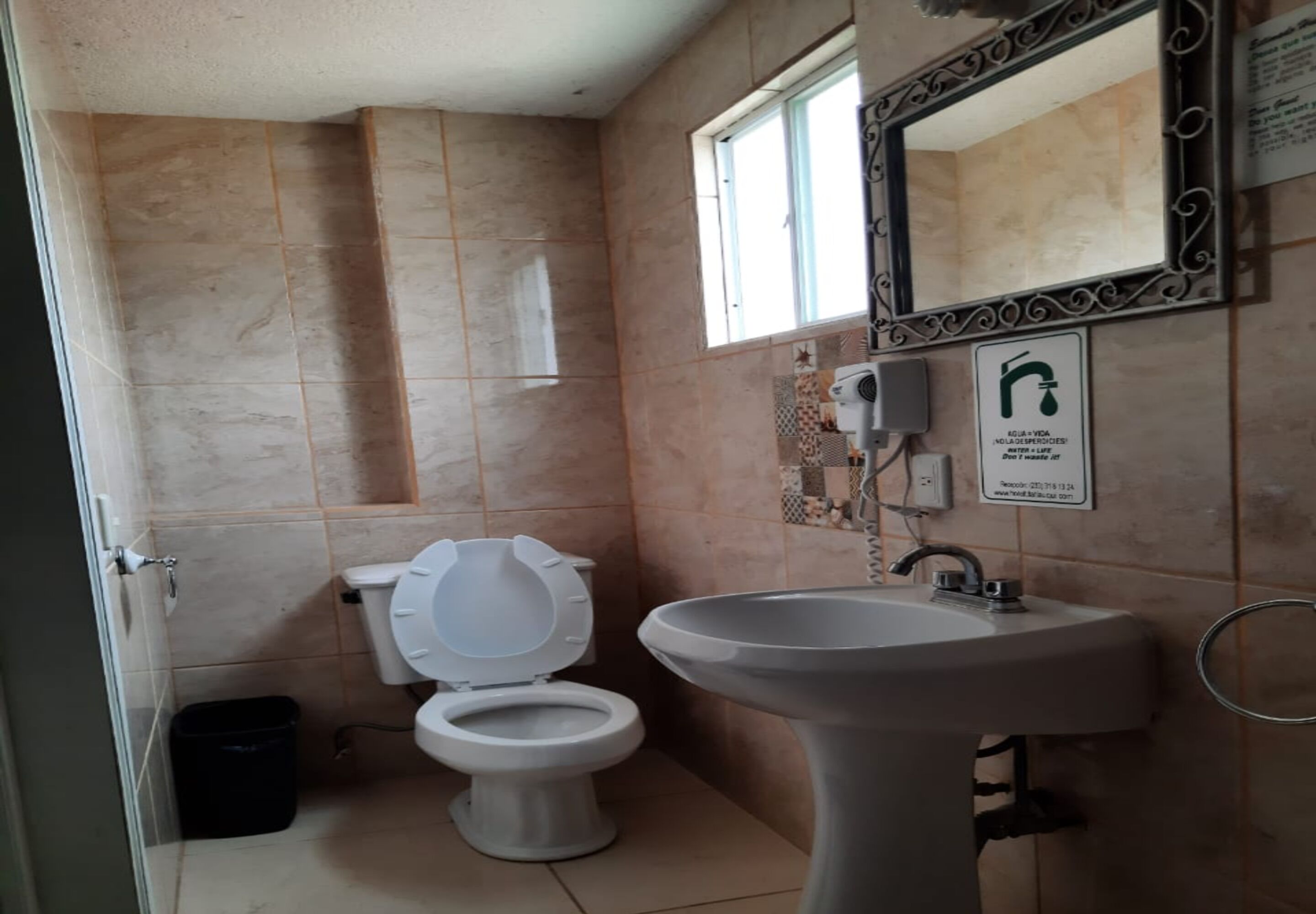 Un baño con inodoro, lavabo y ventana.
