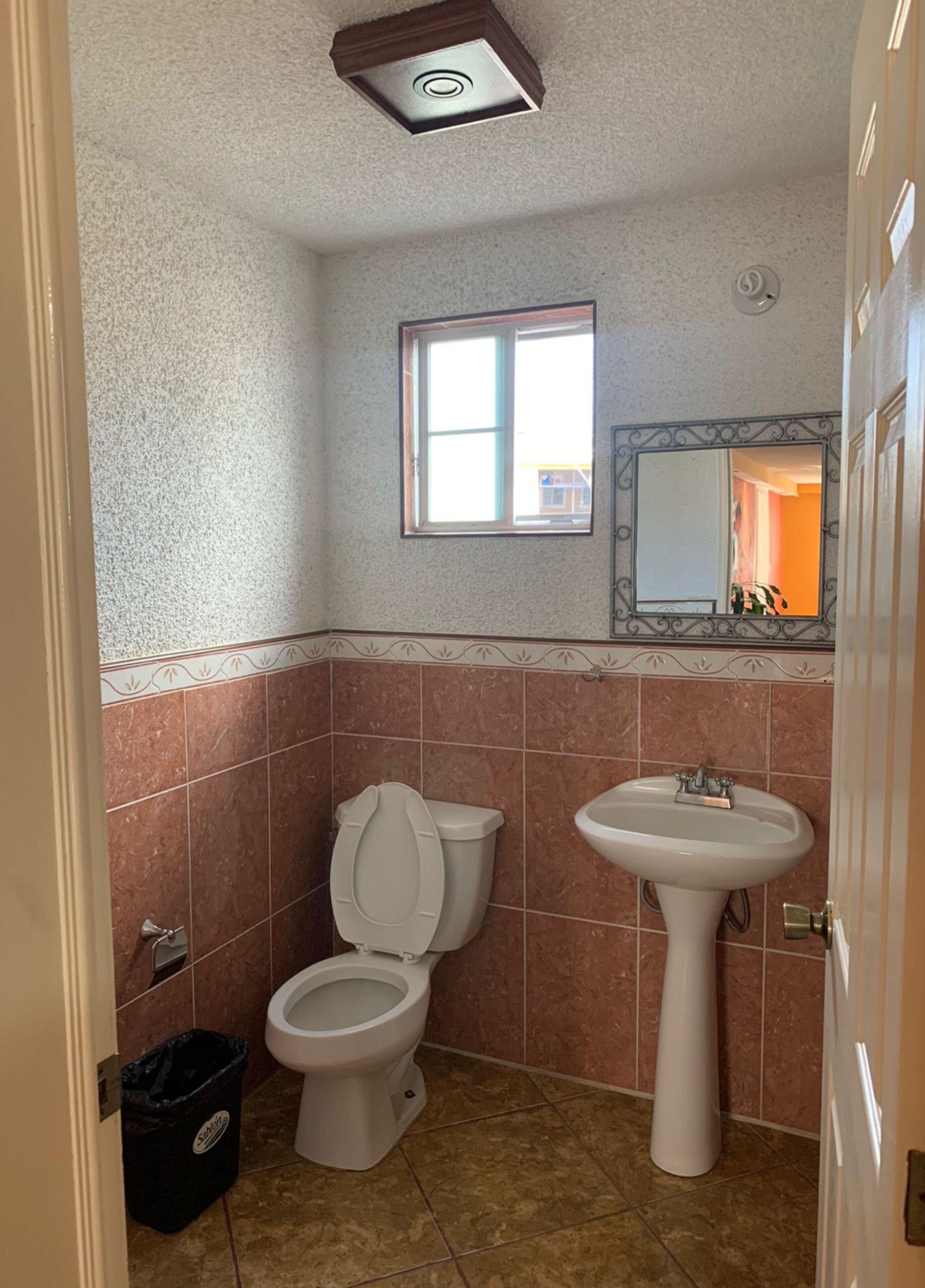 Et badeværelse med toilet, vask og et vindue.