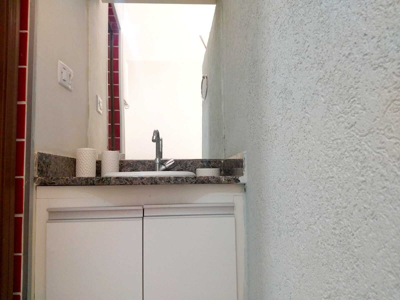 Un baño con un lavamanos blanco, un espejo y un dispensador de toallas.