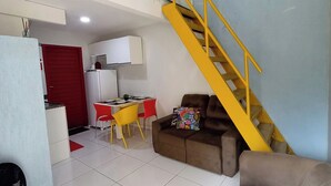 Un espacio habitable compacto con cocina, una mesa de comedor, un sofá y una escalera.