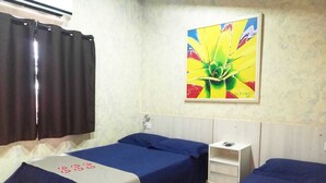 Habitación de hotel con dos camas, un tocador blanco, un cuadro en la pared y una ventana con cortinas.