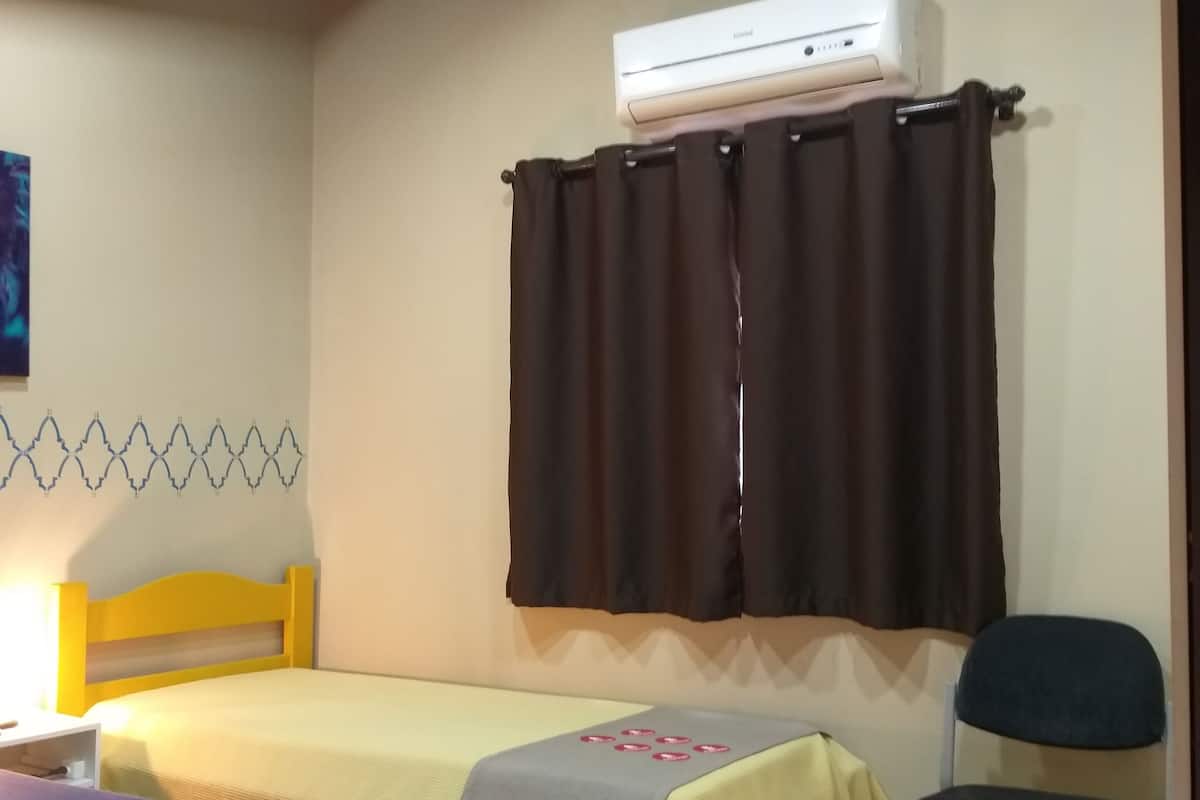 Une chambre avec deux lits, une chaise et un appareil de climatisation.