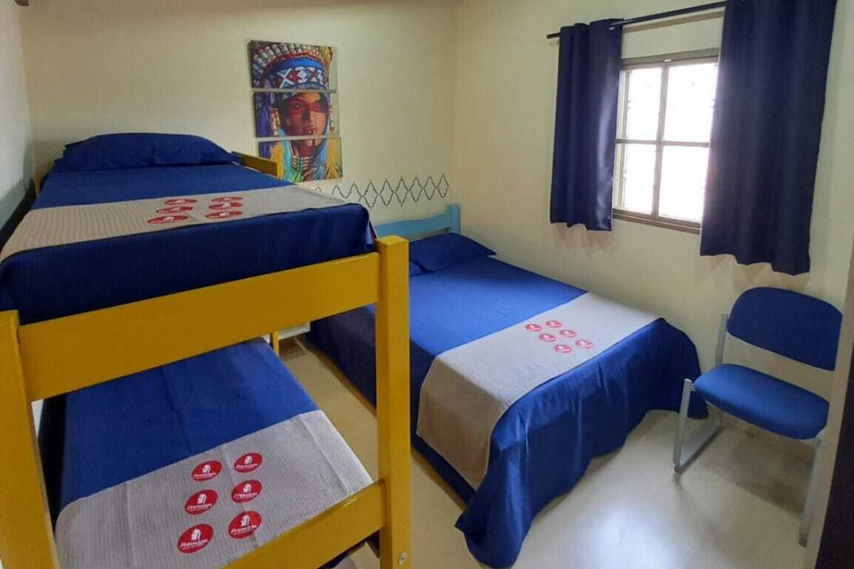 Une chambre de dortoir avec des lits superposés, une chaise, une affiche au mur et un appareil de climatisation.