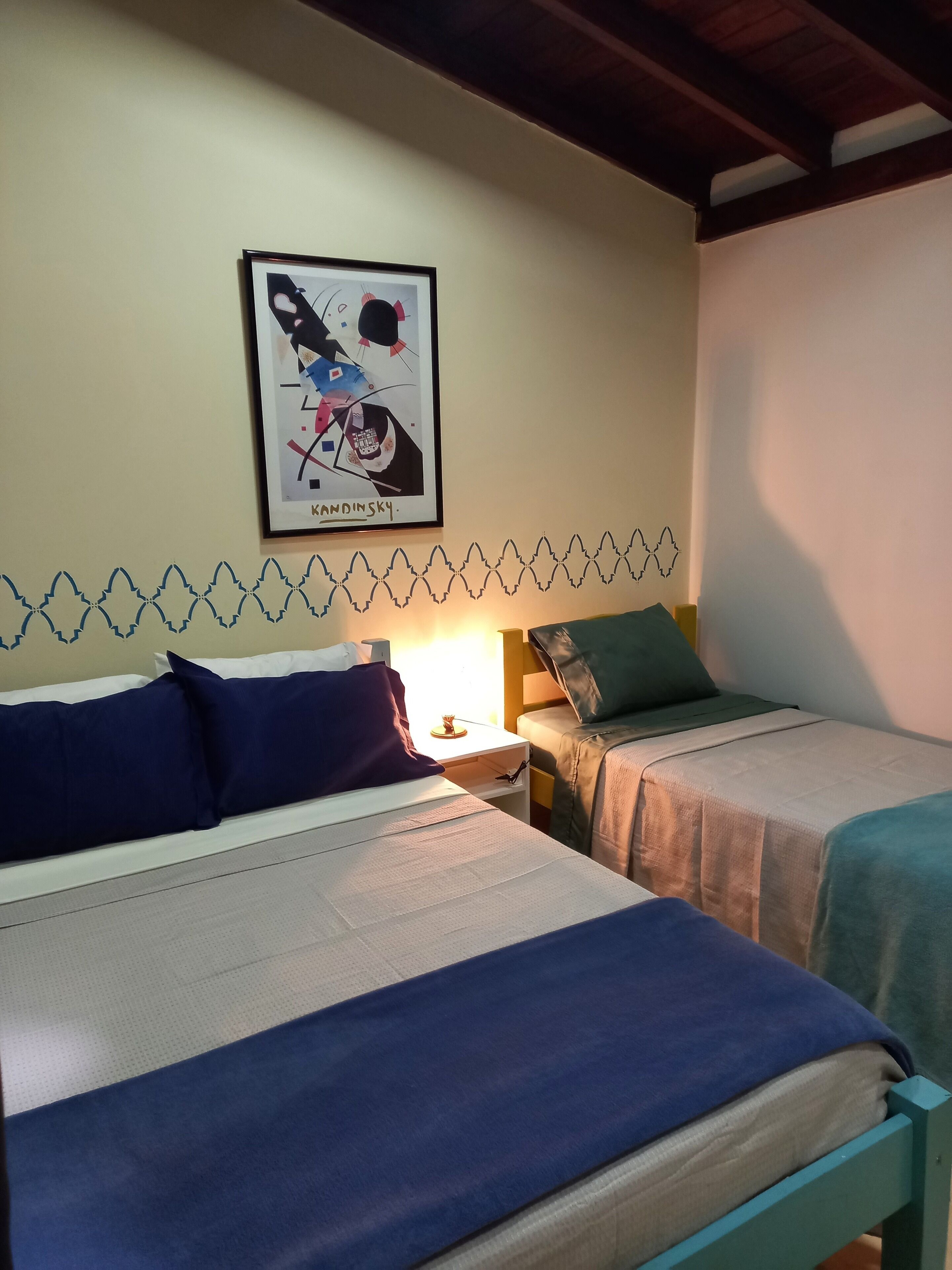 Una habitación con dos camas, un cuadro enmarcado en la pared y un borde decorativo en la pared.
