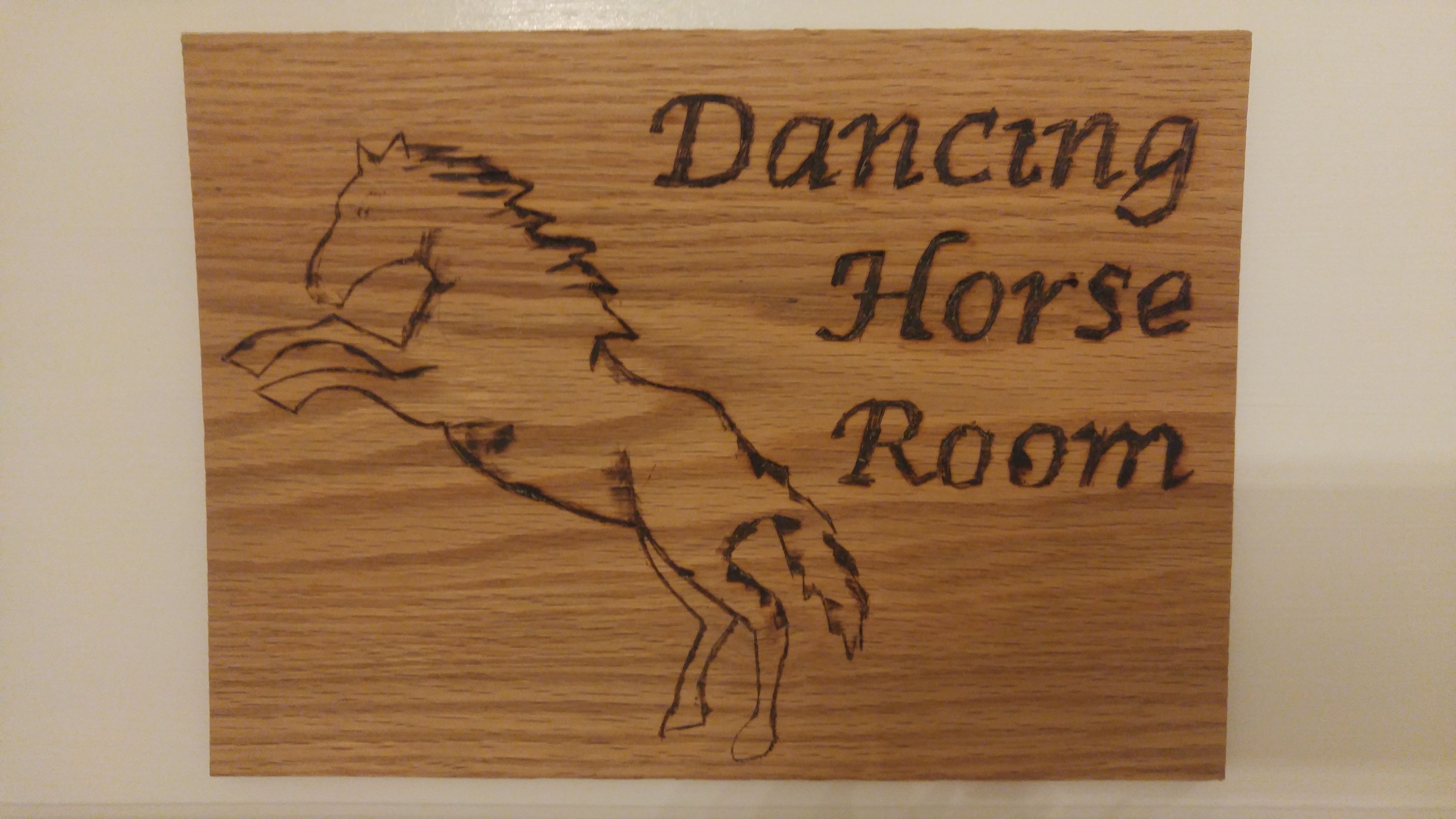 A wooden sign with a horse silhouette and the text "Dancing Horse Room".