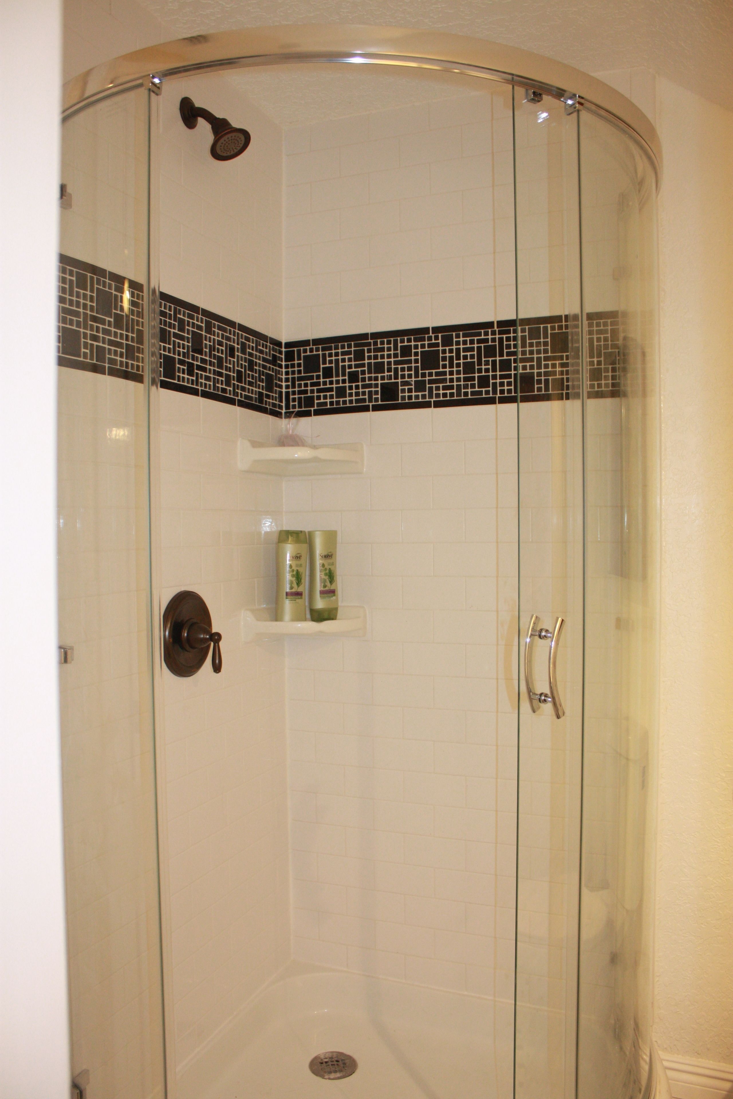 A glass-enclosed shower with a tiled floor and a shelf with toiletries.