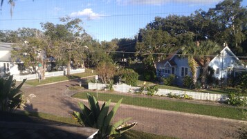 A residential street with houses, a white picket fence, and lush greenery.