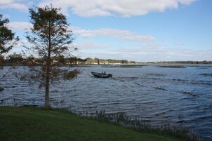 Un lago tranquilo con un bote en el centro, rodeado de árboles y edificios a lo lejos.