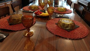 A dining table set with red placemats, golden decorative bowls, and a fruit platter. - Kapp and Kappy B&B (Kissimmee)