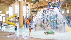 An indoor water park with a large water slide, a pool, and a play area. - Great views! Third floor end unit - Indoor parking!  (Arnolds Park)