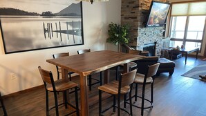A dining area with a wooden table and chairs, a stone fireplace, and a large framed picture on the wall. - Great views! Third floor end unit - Indoor parking!  (Arnolds Park)
