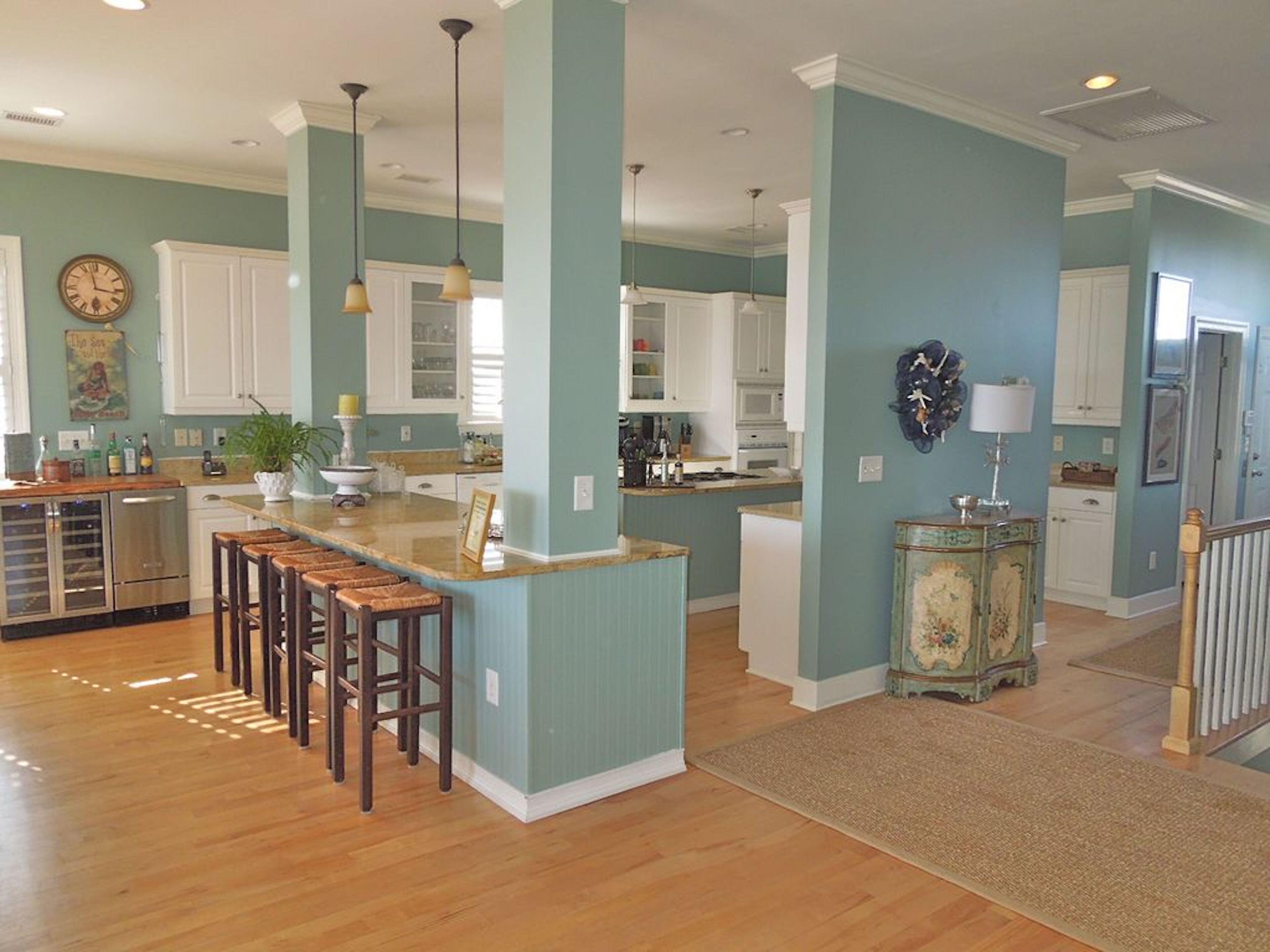 A spacious kitchen with a central island, wooden bar stools, and pendant lighting.