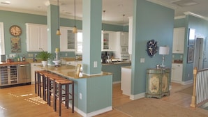 A spacious kitchen with a central island, wooden bar stools, and pendant lighting.