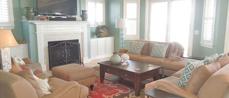 A living room with a fireplace, a television, and a sofa set.