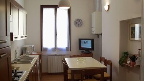 A compact kitchen with a dining area, a TV, and a radiator. - Spacious and bright apartment in Campo S.Alvise (Venezia)
