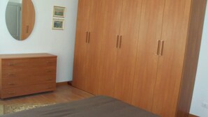 A bedroom with a wooden wardrobe, a dresser, and a bed. - Spacious and bright apartment in Campo S.Alvise (Venezia)