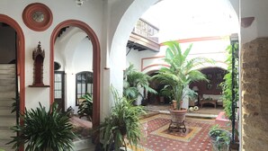 A spacious courtyard with a central staircase, surrounded by arches and potted plants. - Typical Andalusian House (sXVII) (Sanlúcar de Barrameda)