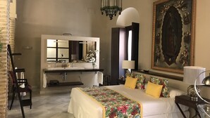 A bedroom with a bed, a desk, a chair, a vanity with a mirror, and a large painting on the wall. - Typical Andalusian House (sXVII) (Sanlúcar de Barrameda)