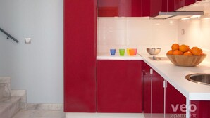 A modern kitchen with red cabinets, a white countertop, and a bowl of oranges. - 2 bedrooms, private terrace (Sevilla)