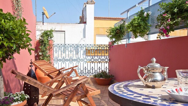 A patio with wooden chairs, a table with a teapot and cup, and potted plants. - 2 bedrooms, private terrace (Sevilla)
