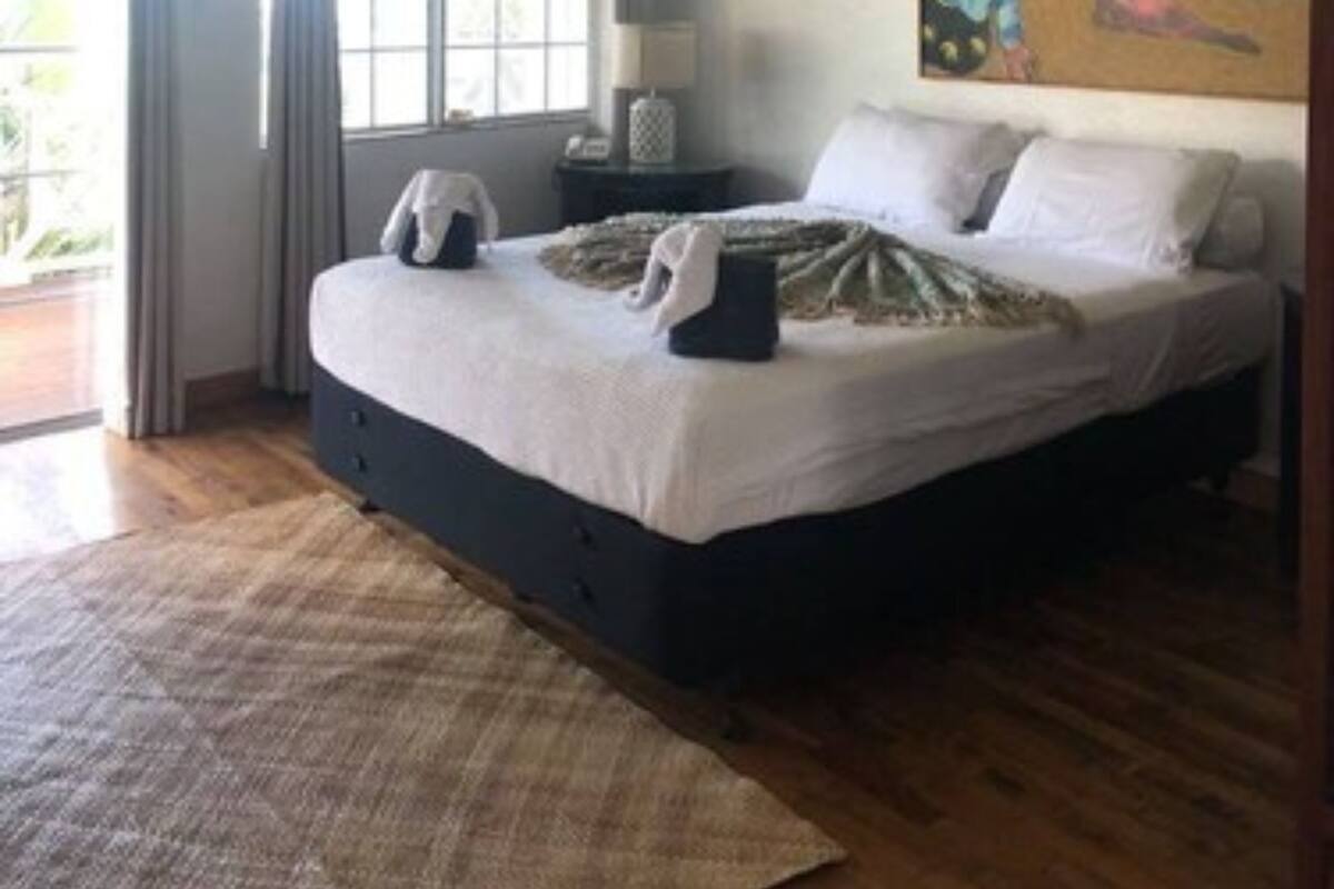 Un dormitorio con una cama grande, una ventana, un cuadro y un equipo de aire acondicionado.